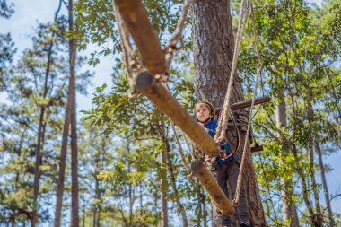 Kasklı mutlu bir çocuk, sağlıklı bir okul çocuğu yaz günü tırmanma parkında eğleniyor.