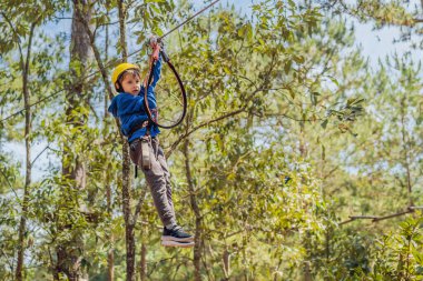 Kasklı mutlu bir çocuk, sağlıklı bir okul çocuğu yaz günü tırmanma parkında eğleniyor.