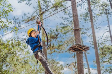 Kasklı mutlu bir çocuk, sağlıklı bir okul çocuğu yaz günü tırmanma parkında eğleniyor.