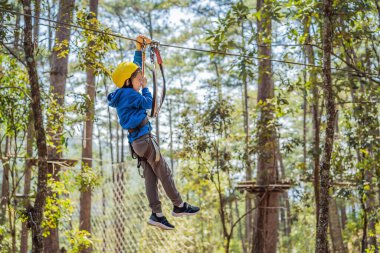 Kasklı mutlu bir çocuk, sağlıklı bir okul çocuğu yaz günü tırmanma parkında eğleniyor.