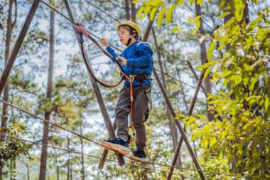 Kasklı mutlu bir çocuk, sağlıklı bir okul çocuğu yaz günü tırmanma parkında eğleniyor.