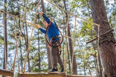 Kasklı mutlu bir çocuk, sağlıklı bir okul çocuğu yaz günü tırmanma parkında eğleniyor.