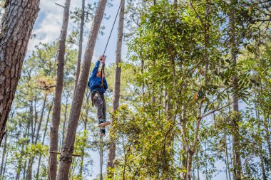 Kasklı mutlu bir çocuk, sağlıklı bir okul çocuğu yaz günü tırmanma parkında eğleniyor.