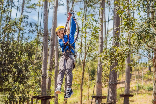 Kasklı mutlu bir çocuk, sağlıklı bir okul çocuğu yaz günü tırmanma parkında eğleniyor.