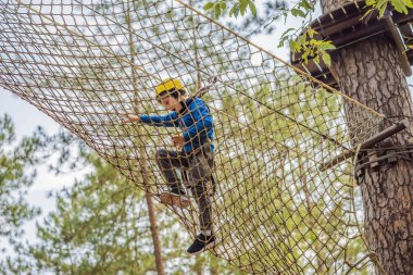 Kasklı mutlu bir çocuk, sağlıklı bir okul çocuğu yaz günü tırmanma parkında eğleniyor.