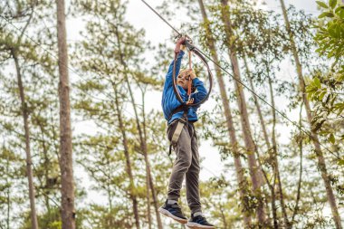 Kasklı mutlu bir çocuk, sağlıklı bir okul çocuğu yaz günü tırmanma parkında eğleniyor.