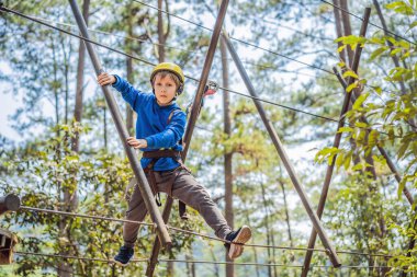 Kasklı mutlu bir çocuk, sağlıklı bir okul çocuğu yaz günü tırmanma parkında eğleniyor.