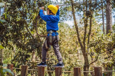 Kasklı mutlu bir çocuk, sağlıklı bir okul çocuğu yaz günü tırmanma parkında eğleniyor.