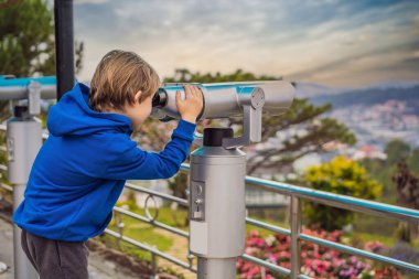 Binoskop. Sabit şehir dürbünü. Bir çocuk şehre dürbünle bakıyor.