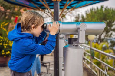 Binoskop. Sabit şehir dürbünü. Bir çocuk şehre dürbünle bakıyor.