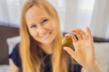 Dijital bir sanatçı olan NFT 'li genç kadın, evdeki tablette dijital sanat eseri yaratıyor ve üzerinde NTF yazan bir madeni para gösteriyor. Uzaktan çalışma, dijital göçebe, dijital resim, animasyon