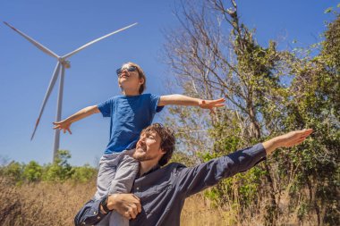 Alternatif enerji, rüzgar çiftliği ve ailenle mutlu zaman geçirmek. Oğlunu omuzlarında taşıyan mutlu baba tatilde ve doğaya kaçıyor. Baba oğlunu omuzlarında taşır ve kollarını sallar.