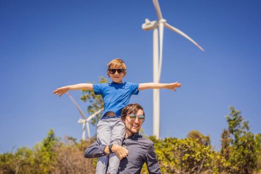Alternatif enerji, rüzgar çiftliği ve ailenle mutlu zaman geçirmek. Oğlunu omuzlarında taşıyan mutlu baba tatilde ve doğaya kaçıyor. Baba oğlunu omuzlarında taşır ve kollarını sallar.