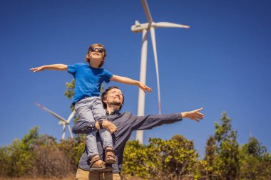 Alternatif enerji, rüzgar çiftliği ve ailenle mutlu zaman geçirmek. Oğlunu omuzlarında taşıyan mutlu baba tatilde ve doğaya kaçıyor. Baba oğlunu omuzlarında taşır ve kollarını sallar.