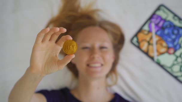 Artista digital mujer, pintora contemporánea sostiene una moneda NFT en su mano. Ella también está feliz porque está participando en un nuevo movimiento de venta de formas de arte utilizando la tecnología blockchain. NFT monedas son — Vídeo de stock
