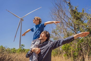 Alternatif enerji, rüzgar çiftliği ve ailenle mutlu zaman geçirmek. Oğlunu omuzlarında taşıyan mutlu baba tatilde ve doğaya kaçıyor. Baba oğlunu omuzlarında taşır ve kollarını sallar.