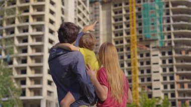 Bir aile babası, anne ve oğlu inşaat halinde olan yüksek bir binaya bakıyorlar. Nereden daire almaları gerektiğini tartışıyorlar.