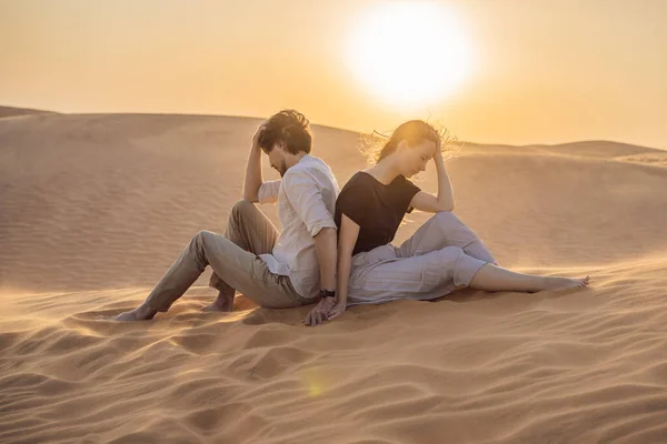 Relationship problems between a couple - a man and a woman. Family conflict. Man and woman have a heated relationship, sit in the hot desert with their backs to each other and do not want to talk