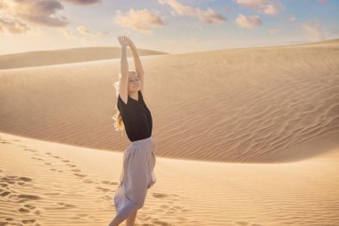 Çölde seyahat eden genç ve güzel bir kadın. Güneşli yaz gününde kumullar ve mavi gökyüzü. Seyahat, macera, özgürlük konsepti. COVID 19 karantinasından sonra turizm yeniden açıldı