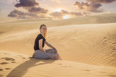Çölde seyahat eden genç ve güzel bir kadın. Güneşli yaz gününde kumullar ve mavi gökyüzü. Seyahat, macera, özgürlük konsepti. COVID 19 karantinasından sonra turizm yeniden açıldı
