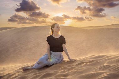 Çölde seyahat eden genç ve güzel bir kadın. Güneşli yaz gününde kumullar ve mavi gökyüzü. Seyahat, macera, özgürlük konsepti. COVID 19 karantinasından sonra turizm yeniden açıldı