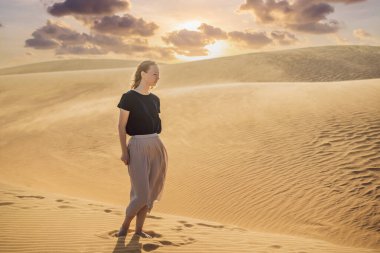 Çölde seyahat eden genç ve güzel bir kadın. Güneşli yaz gününde kumullar ve mavi gökyüzü. Seyahat, macera, özgürlük konsepti. COVID 19 karantinasından sonra turizm yeniden açıldı
