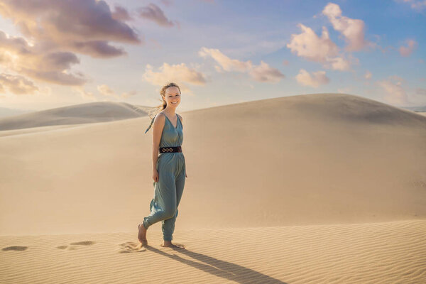 Молодая красивая женщина путешествует по пустыне. Песчаные дюны и голубое небо в солнечный летний день. Путешествия, приключения, свобода концепции. Туризм возобновляется после карантинного COVID 19