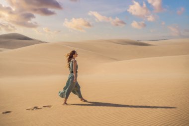 Çölde seyahat eden genç ve güzel bir kadın. Güneşli yaz gününde kumullar ve mavi gökyüzü. Seyahat, macera, özgürlük konsepti. COVID 19 karantinasından sonra turizm yeniden açıldı