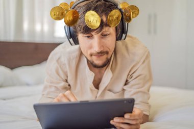 Dijital bir sanatçı olan genç adam, DJ evdeki tablette dijital sanat eseri yaratıyor ve üzerinde NTF yazan bir madeni para gösteriyor. Uzaktan çalışma, dijital göçebe, dijital resim, animasyon, video