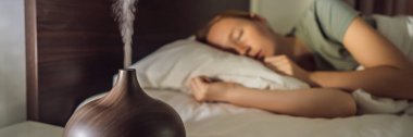BANNER, Aromaterapi Konsepti. Tahta Elektronik Ultrasonik Temel Yağ Aroma Yayıcı ve Nemlendirici. Ev için ultrasonik aroma yayıcı. Kadın evinde dinleniyor.