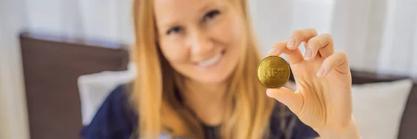 BANNER, LONG FORMAT NFT Young woman, a digital artist, creates digital art on a tablet at home and shows a coin with the inscription NTF - non fungible token. Remote work, digital nomad, digital — Stock Photo, Image