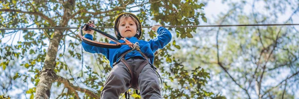 BANNER, LONG FORMAT Szczęśliwe dziecko w kasku, zdrowy młodzieniec szkolny cieszący się aktywnością w parku przygód wspinaczkowych w letni dzień — Zdjęcie stockowe