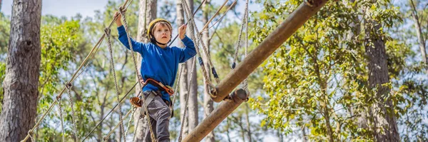 BANNER, LANG FORMAAT Gelukkig kind in een helm, gezonde tiener schooljongen genieten van activiteit in een klimpark op een zomerse dag — Stockfoto