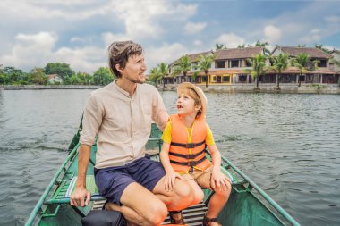 Baba ve oğul turistler Tam Coc gölünde, Ninh Binh, Vietnam. UNESCO Dünya Mirası Alanı 'dır ve tekne mağarası turlarıyla ünlüdür. Vietnam topraklarındaki Halong Körfezi. Vietnam sınırları yeniden açıyor