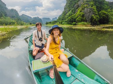 Tam Coc, Ninh Binh, Vietnam gölündeki mutlu aile turistleri. UNESCO Dünya Mirası Alanı 'dır ve tekne mağarası turlarıyla ünlüdür. Vietnam topraklarındaki Halong Körfezi. Vietnam yeniden açılıyor