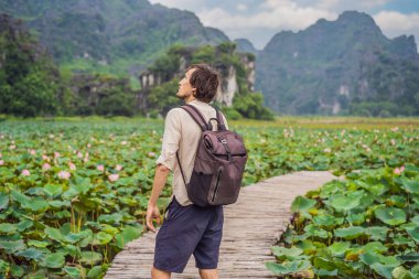 Lotus Gölü 'nün ortasındaki yolda bir adam. Mua Mağarası, Ninh Binh, Vietnam. Vietnam, Coronovirus COVID 19 konseptinden sonra yeniden açıldı.