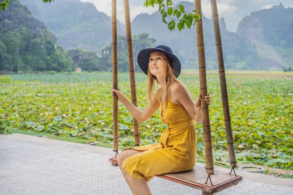 Jeune femme se balance sur une balançoire sur le champ de lotus — Photo