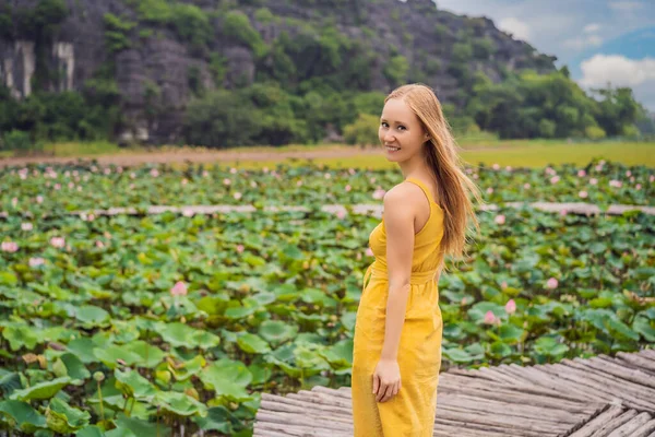 Jovem em um vestido amarelo no caminho entre o lago de lótus. Mua Cave, Ninh Binh, Vietname. Vietname reabre após quarentena Coronovirus COVID 19 conceito — Fotografia de Stock