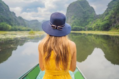 Tam Coc gölündeki kadın turist, Ninh Binh, Vietnam. UNESCO Dünya Mirası Alanı 'dır ve tekne mağarası turlarıyla ünlüdür. Vietnam topraklarındaki Halong Körfezi. Vietnam sonra sınırları yeniden açıyor