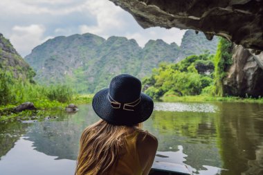 Tam Coc gölündeki kadın turist, Ninh Binh, Vietnam. UNESCO Dünya Mirası Alanı 'dır ve tekne mağarası turlarıyla ünlüdür. Vietnam topraklarındaki Halong Körfezi. Vietnam sonra sınırları yeniden açıyor