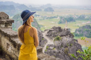 Hang Mua Tapınağı 'nın tepesindeki kadın turist, pirinç tarlaları, Ninh Binh, Vietnam. Vietnam, Coronovirus COVID 19 karantinasından sonra sınırları yeniden açıyor.