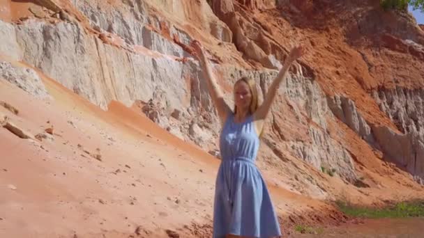 Eine Frau geht an einem roten Canyon oder Feenbach am Rande der Wüste im Dorf Mui Ne in Südvietnam entlang — Stockvideo