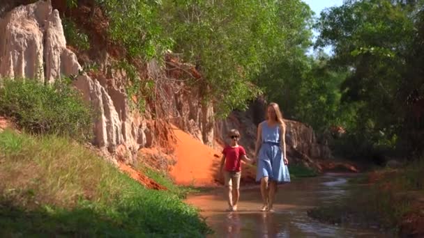 Eine Familie spaziert im Dorf Mui Ne in Südvietnam an einem roten Canyon oder Feenbach am Rande der Wüste entlang — Stockvideo