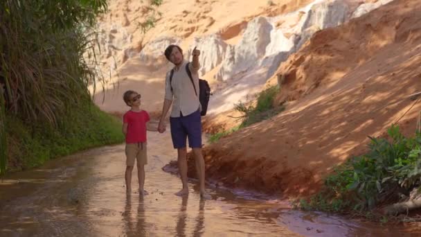 Una famiglia cammina lungo un canyon rosso o un ruscello fatato al confine del deserto nel villaggio di Mui Ne nel Vietnam meridionale — Video Stock