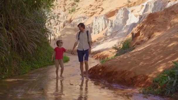 Una familia camina a lo largo de un cañón rojo o arroyo de hadas en la frontera del desierto en el pueblo de Mui Ne en el sur de Vietnam — Vídeos de Stock