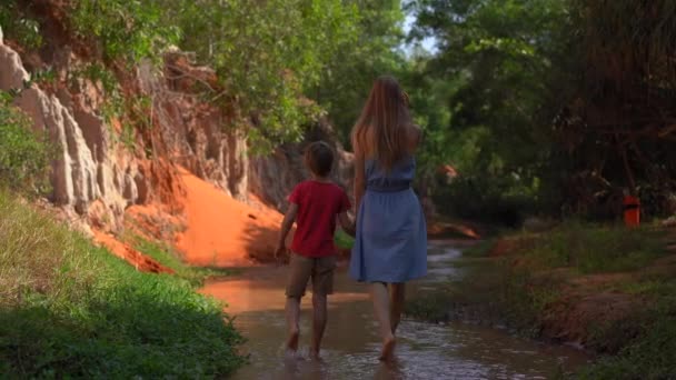 Une famille marche le long d'un canyon rouge ou d'un ruisseau de fées à la frontière du désert dans le village de Mui Ne dans le sud du Vietnam — Video