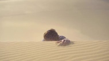 Ofis kıyafetli bir adam çölde bir kum tepesine tırmanıyor. İş dünyasındaki zorlukların üstesinden gelmek