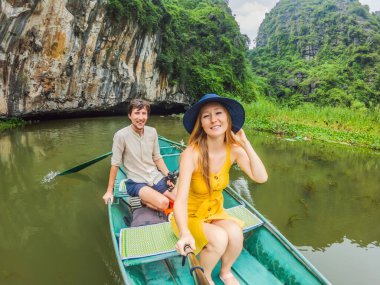 Tam Coc, Ninh Binh, Vietnam gölündeki mutlu aile turistleri. UNESCO Dünya Mirası Alanı 'dır ve tekne mağarası turlarıyla ünlüdür. Vietnam topraklarındaki Halong Körfezi. Vietnam yeniden açılıyor