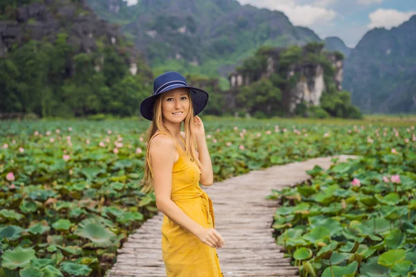 Jovem em um vestido amarelo no caminho entre o lago de lótus. Mua Cave, Ninh Binh, Vietname. Vietname reabre após quarentena Coronovirus COVID 19 conceito — Fotografia de Stock