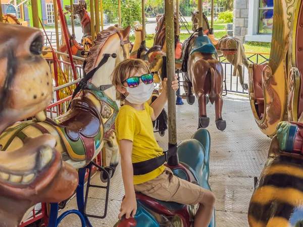 Garçon portant un masque médical pendant le coronavirus COVID-19 dans un parc d'attractions — Photo